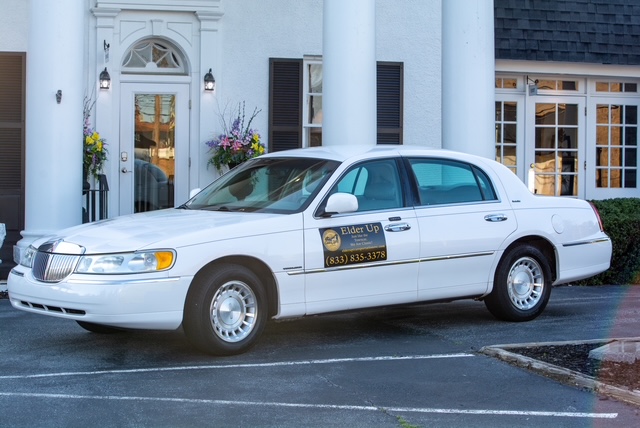The white Elder Up Lincoln Town Car at a columned building entrance